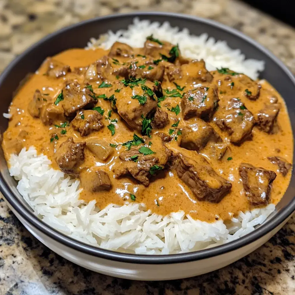 A large pan of homemade beef stroganoff served family-style with crusty bread and a side salad, perfect for gatherings.